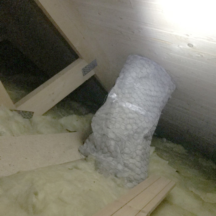 Isolerat ventilationsrör på vinden med synbart fuktproblem och rester efter städning av getingbo.