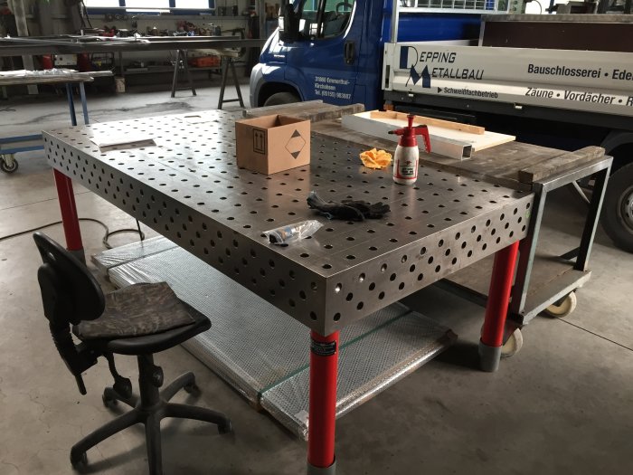 Svetsbord i verkstad med hålmönster, verktyg och svetstillbehör på ytan.