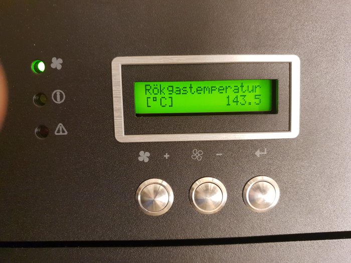 Digital display som visar rök gastemperatur på 143.5 grader Celsius på en värmesystempanel.