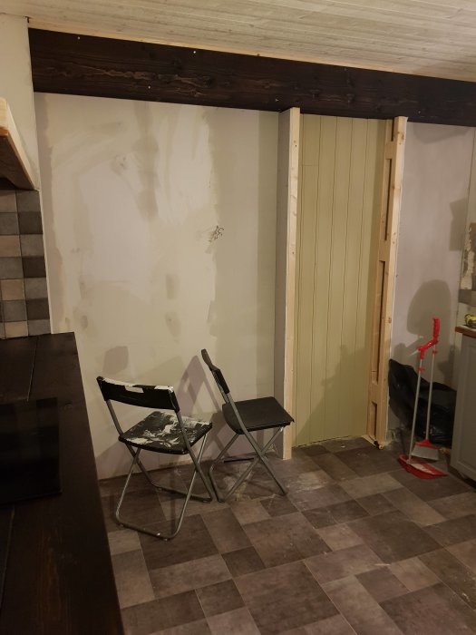 Bilden visar en oavslutad renovering av ett skafferi med en uppsatt träbalk och pågående panelarbete.