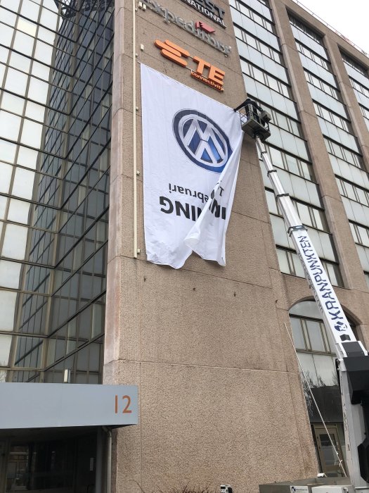 Reklamflagga för Volkswagen upp och ned på en byggnadsfasad.