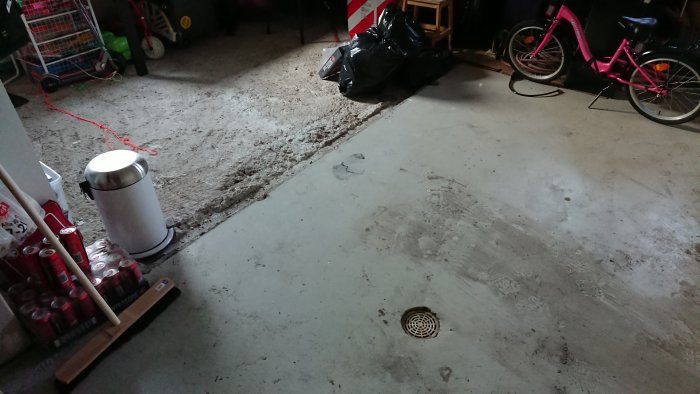 Halvfärdigt garagegolv med ojämnt underlag samt betong och byggmaterial är synligt.