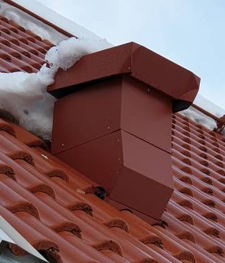 Röd skorsten där övre och nedre delar är korrekt installerade på ett snötäckt tak.