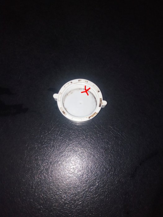 Vit cirkulär plugg med röd markering där det läcker och utan synlig gul markering.