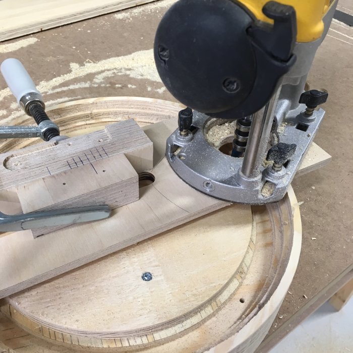 En handöverfräs som formar en träkomponent med cirkulär guide och spånskaping.