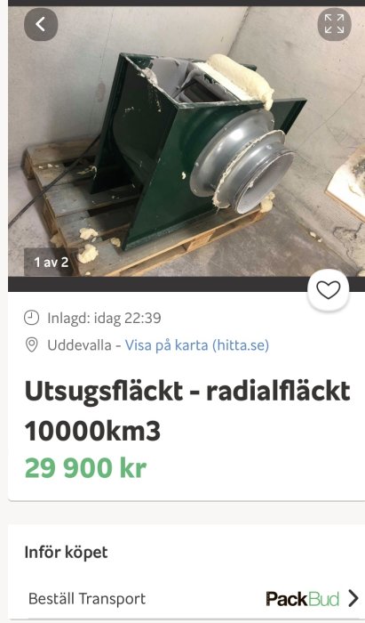 Industriell radialfläkt i grönt på pall i ett lagerutrymme.