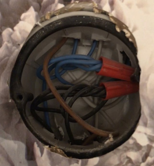 Gamla eldosor med blå, brun, röd och svarta kablar i en vägg.