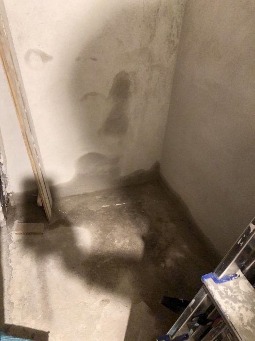 Fuktfläckar i källarhörn med synligt vatten på betonggolvet och väggar efter snösmältning.