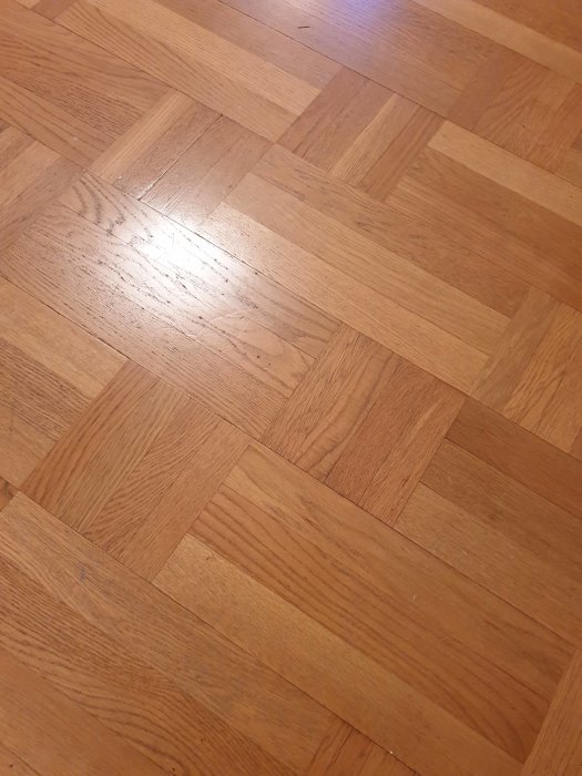 Laminatgulv med parkettmønster i fiskebensdesign, lys brun farge.