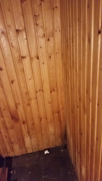 Träpanel på vägg med fuktmarkeringar i hörnet innan rivning på grund av besiktningsråd.