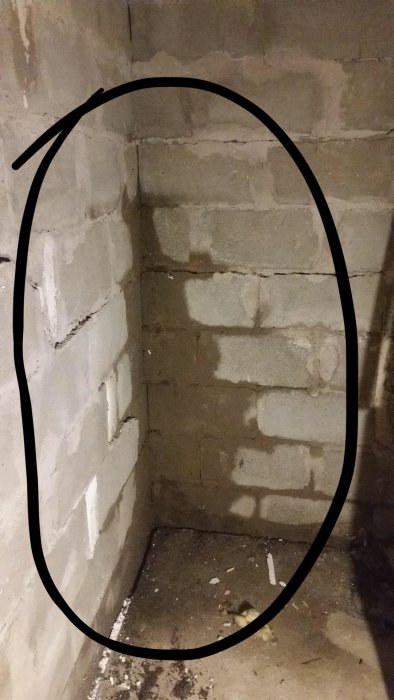 Gammal tegelvägg markerad med svart oval där rosa isolering har tagits bort, före renovering.
