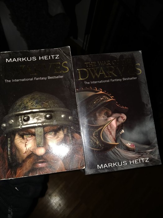 Två fantasyböcker av Markus Heitz, "Dwarves" och "The War of the Dwarves", hålls upp.