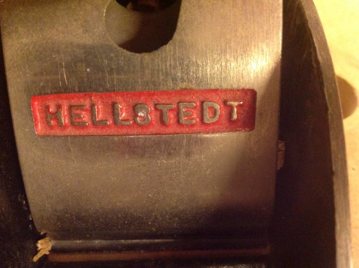 Närbild av etiketten på en svensk hyvel med texten "HELLSTEDT" mot en metallbakgrund.