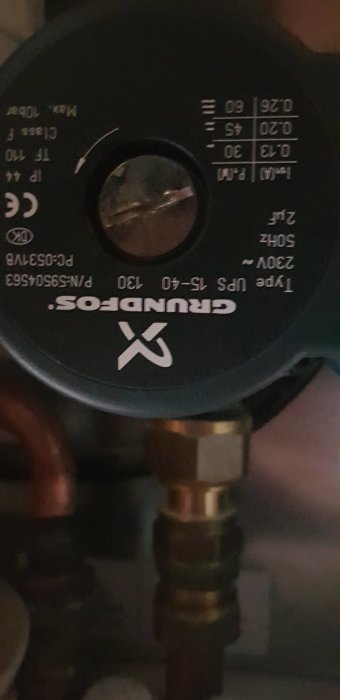 Närbild på en äldre Grundfos cirkulationspump som sitter installerad, med fokus på pumpens inställningstopp.