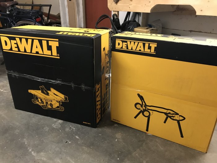 Förpackningar av Dewalt 7491 bordssåg och stativ i en verkstadsmiljö.