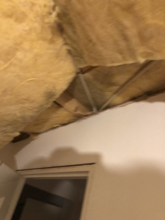 Tak utan paneler med synlig isolering och en takstol vid en väggkant.