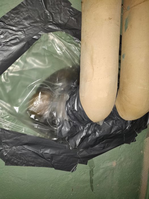 Isolerade fjärrvärmerrör täckta med svart plast för att försöka blockera luftflöde.