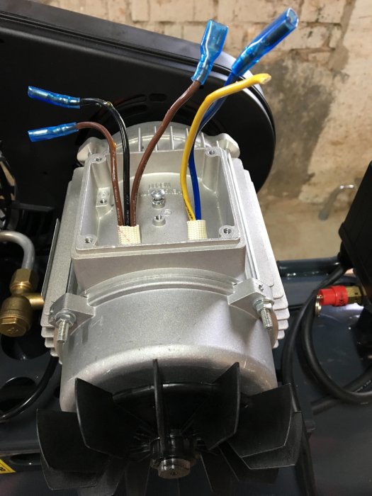 Öppen kopplingslåda för enfas kompressor med fem utstickande ledningar, varav två är kopplade till kondensatorer.