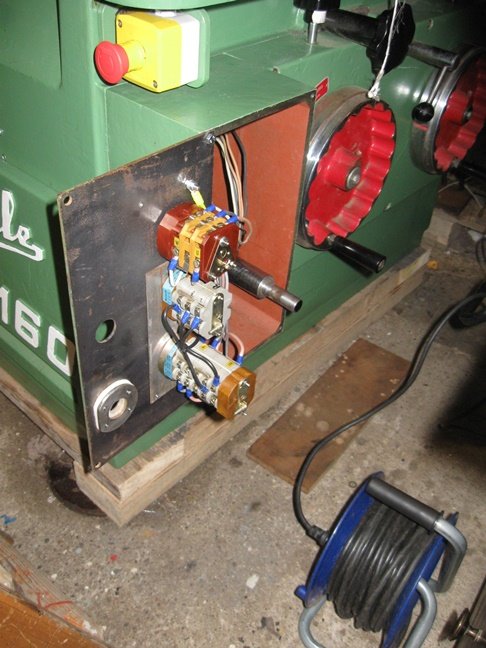 Manöverpanel på maskin med öppet kapsling och synliga elektriska komponenter, oljekoppar syns monterade.
