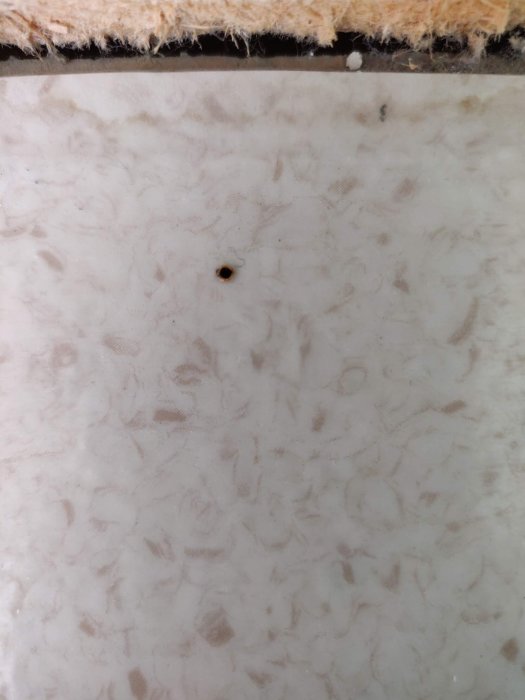 Golv med bränt litet hål för att testa om det är plastmatta eller linoleum.