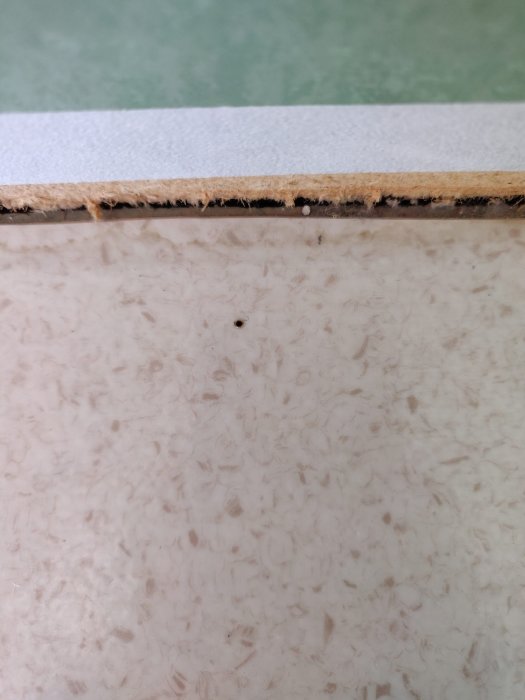 Närbild på en golvsektion där ett märke syns efter ett test med varmt gem för att identifiera golvmaterial.