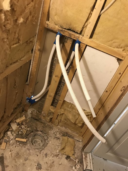 Omfattande badrumsrenovering med synliga rörinstallationer och isolering i väggar, samt avlopp i golv.