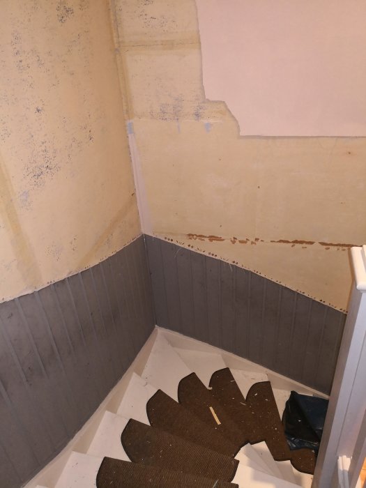 Trapprenovering pågår med otapetserade väggar och en trapp med höjdskillnader.
