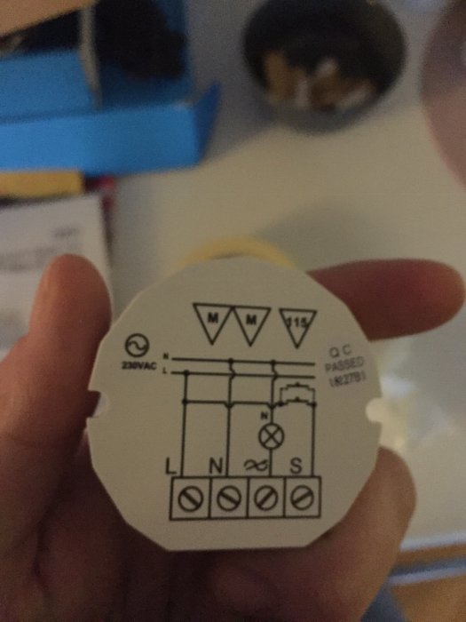 Närbild på en hand som håller en Vadsbo dimmerpuck med kopplingsschema.