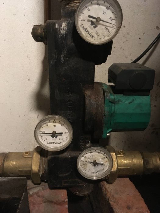 Laddomat med termometrar som visar temperaturer i ett värmesystem, kondens synlig på en termometer.