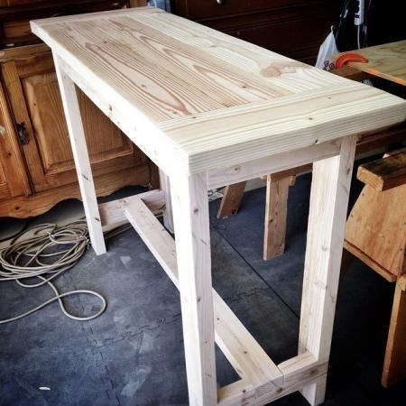 Hemmagjort bord byggt av vanliga träreglar med synliga skruvar, i en verkstadslokalis.