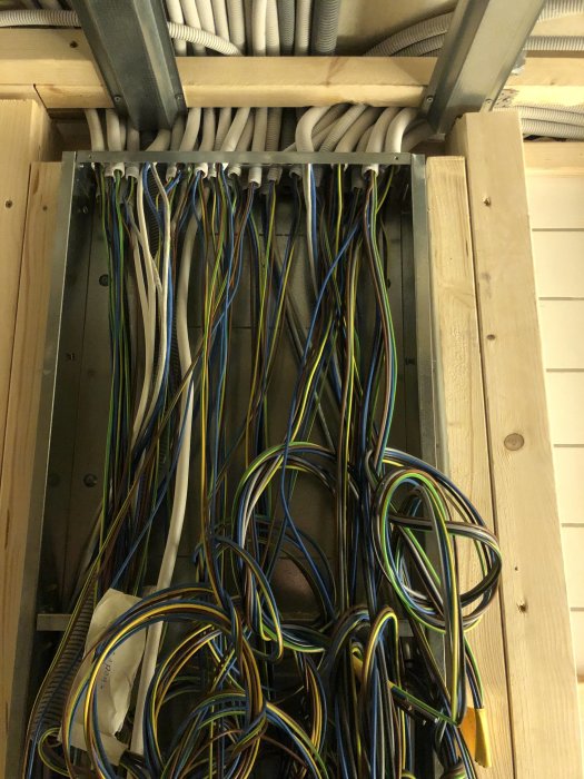 Öppen kabeldragning med en mängd oorganiserade elektriska kablar under en renovering.