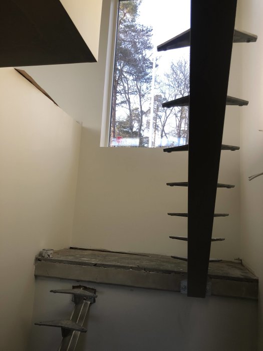 Orenoverad trappa med trästeg och pelare utan räcke framför ett fönster.