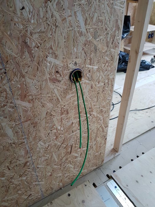 KNX-kabel dragen genom vägg med OSB-skiva vid en kopplingspunkt i ett hus under renovering.