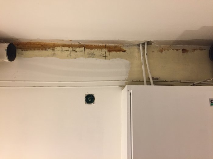 Öppning i tak med synliga markeringar och mått, nära tillstötande vägg och köksskåp.
