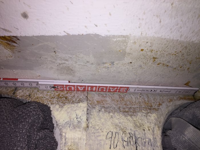 Måttband visar 250 cm på en byggnadsyta med borrspån och markeringar.