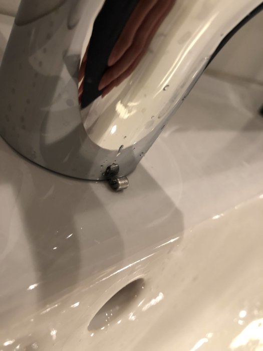 Närbild på ett vitt handfat med en metallögla framför blandarens bas.