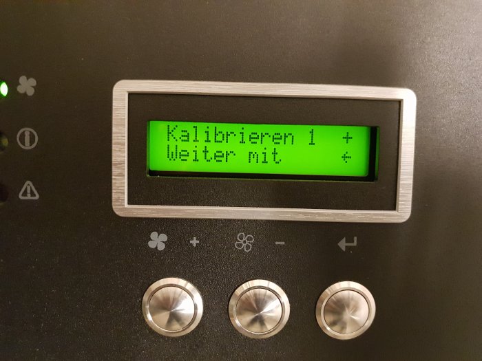 Digital skärm med tysk text 'Kalibrieren 1 + Weiter mit' och kontrollknappar på en apparat.