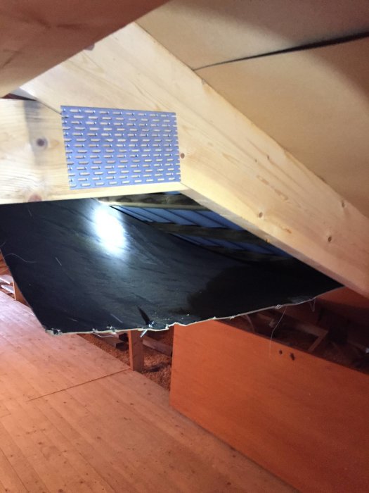 Undertaksskiva som har lossnat och hänger ner från vinden i ett hus.
