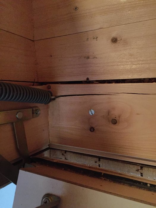 Skadad vindstrappa med sprucket trä och böjd metallkonstruktion där fjädrar är fästa, behöver potentiell reparation.