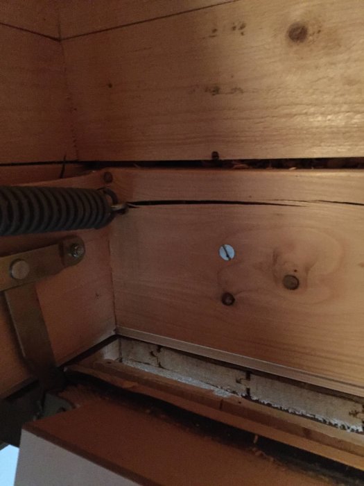 Vindstrappa med sprucken träbit där fjädrarna är fästa, vilket orsakat en böj på metallen.