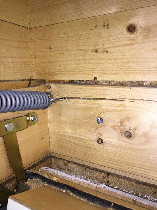 Sprucken träbit där fjädern till en vindstrappa är fäst, vilket orsakat böj på konstruktionen.