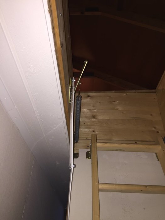 Böjd vindstrappskonstruktion med sprucket trä och synliga metallfjädrar i ett hus från 1970.