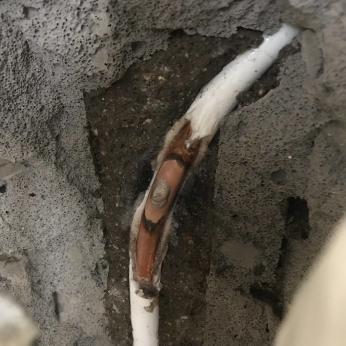 Reparerad uppvärmningsrör med lödd och tätad koppling i en betongvägg.