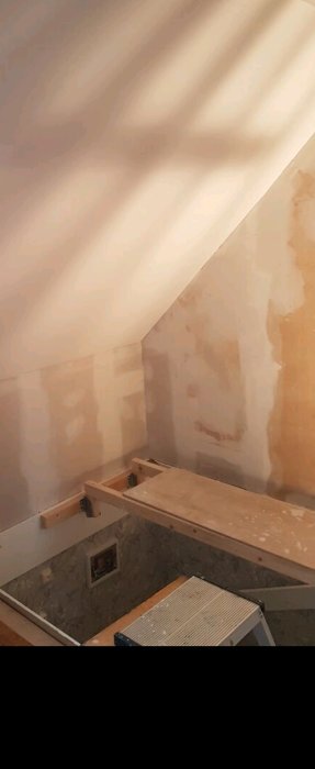 Renoveringsprojekt med balkskor och reglar som stöd för en spånskiva i ett rum under konstruktion.