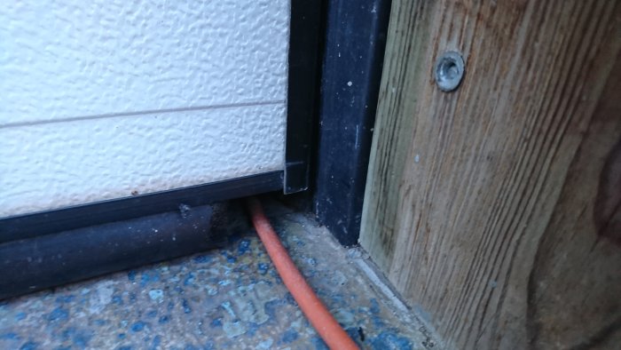 Närbild på skadad tätningslist vid garageport där möss har gnagt hål.