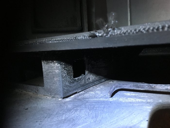 Närbild av löst spjällspak i en vedeldad spis som behöver reparation.