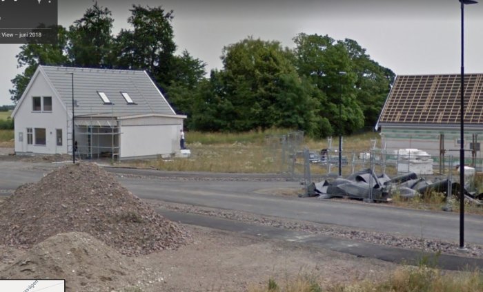 Nybyggt hus vid en gata med byggmaterial och en grushög i förgrunden, tagen från Google Maps.