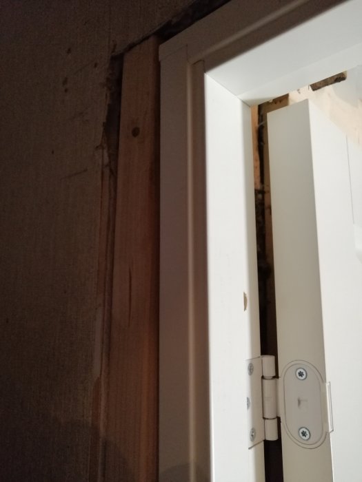 Justerad dörrkarm fastsatt med karmskruvar för att stå rakt mot en ojämn vägg.