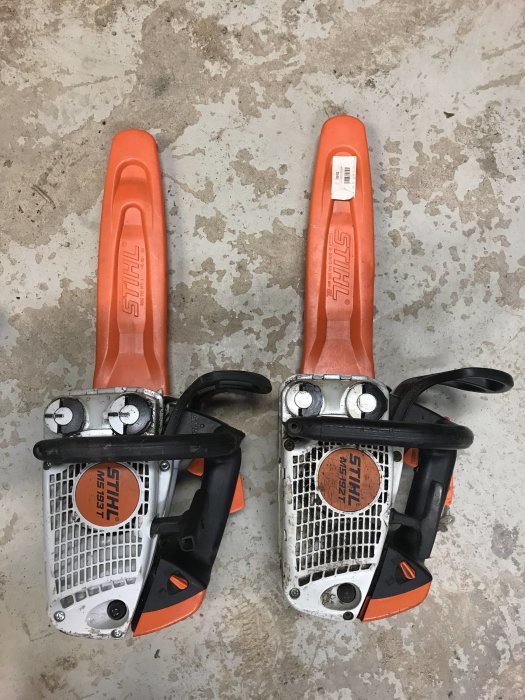 Två Stihl motorsågar ligger på ett grått betonggolv.