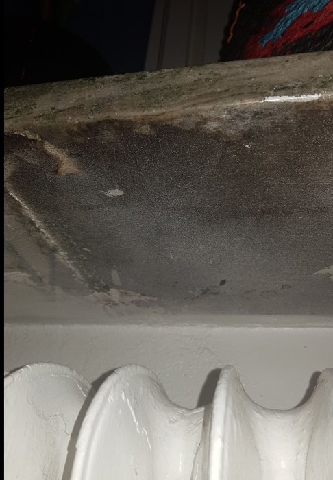 Närbild på underdelen av en fönsterbräda i stenmaterial över ett element.
